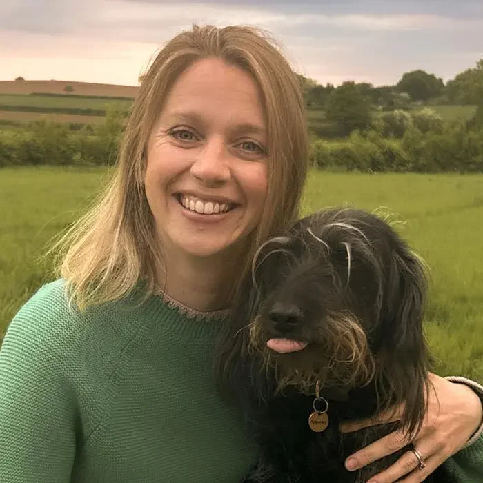 kate from nova vets hugging dog in field